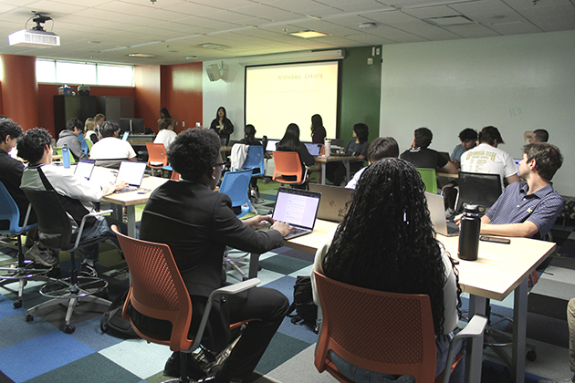 group of students sitting at desks in a classroom with their backs to the camera