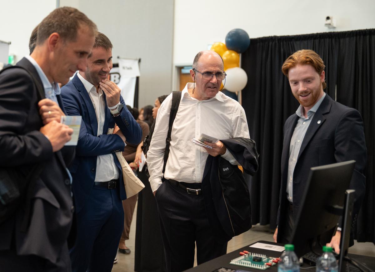 Attendees observe a demonstration of a mechanical device at a Georgia Tech innovation showcase.