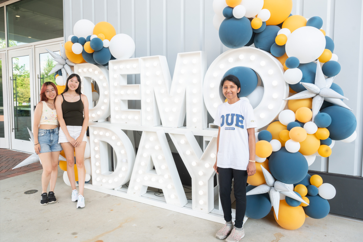 three girls standing next to big demo day letters